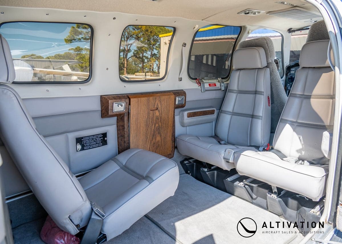The interior of a Beechcraft Bonanza with gray leather seats and a cargo net.
