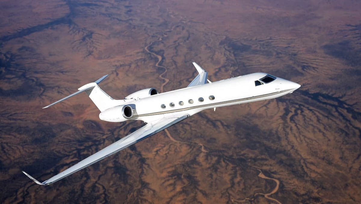 Gulfstream G550 in flight over a desert landscape.