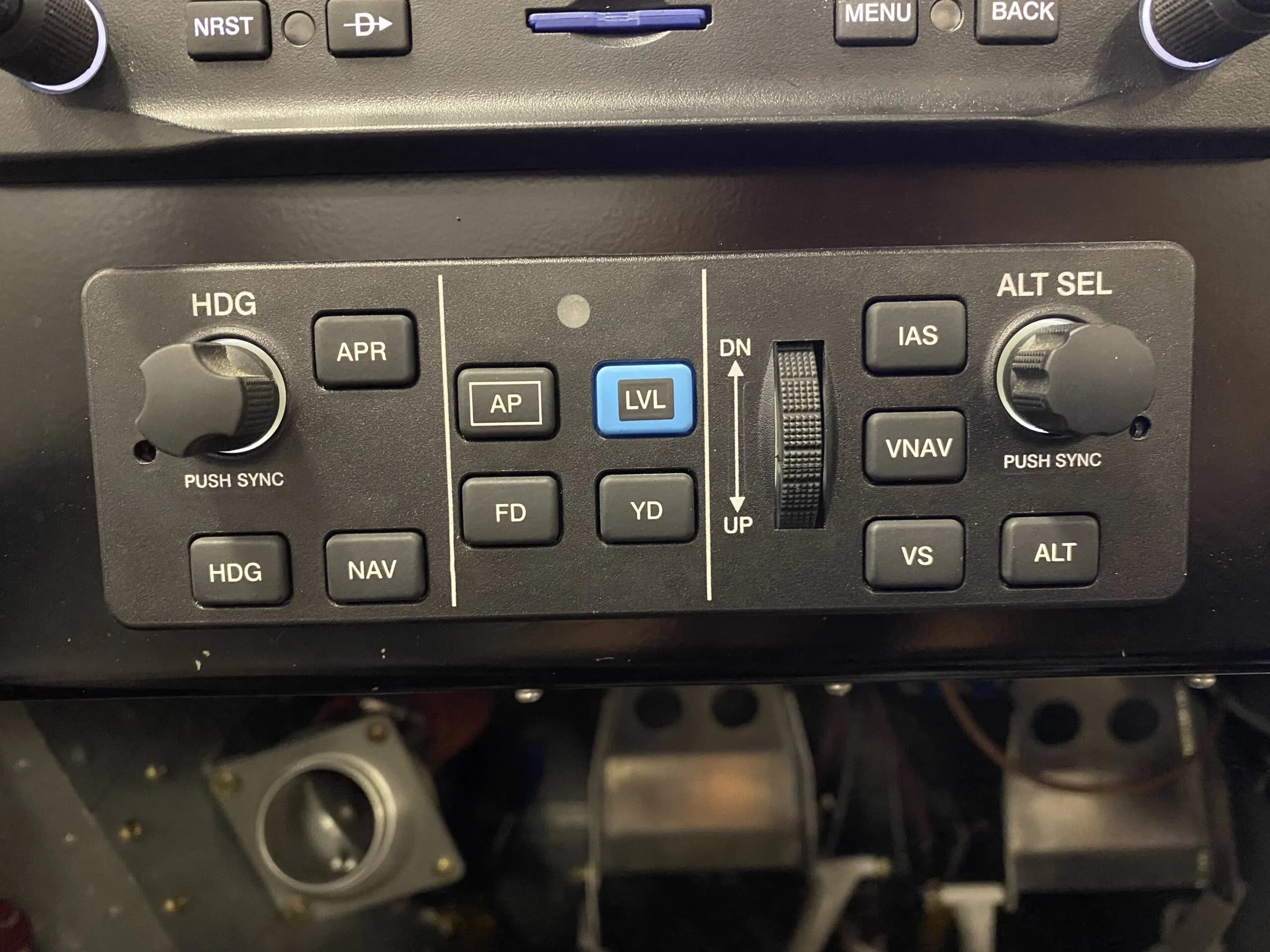 A close-up view of an aircraft autopilot control panel with buttons for HDG, APR, AP, FD, YD, LVL, IAS, VNAV, VS, and ALT.