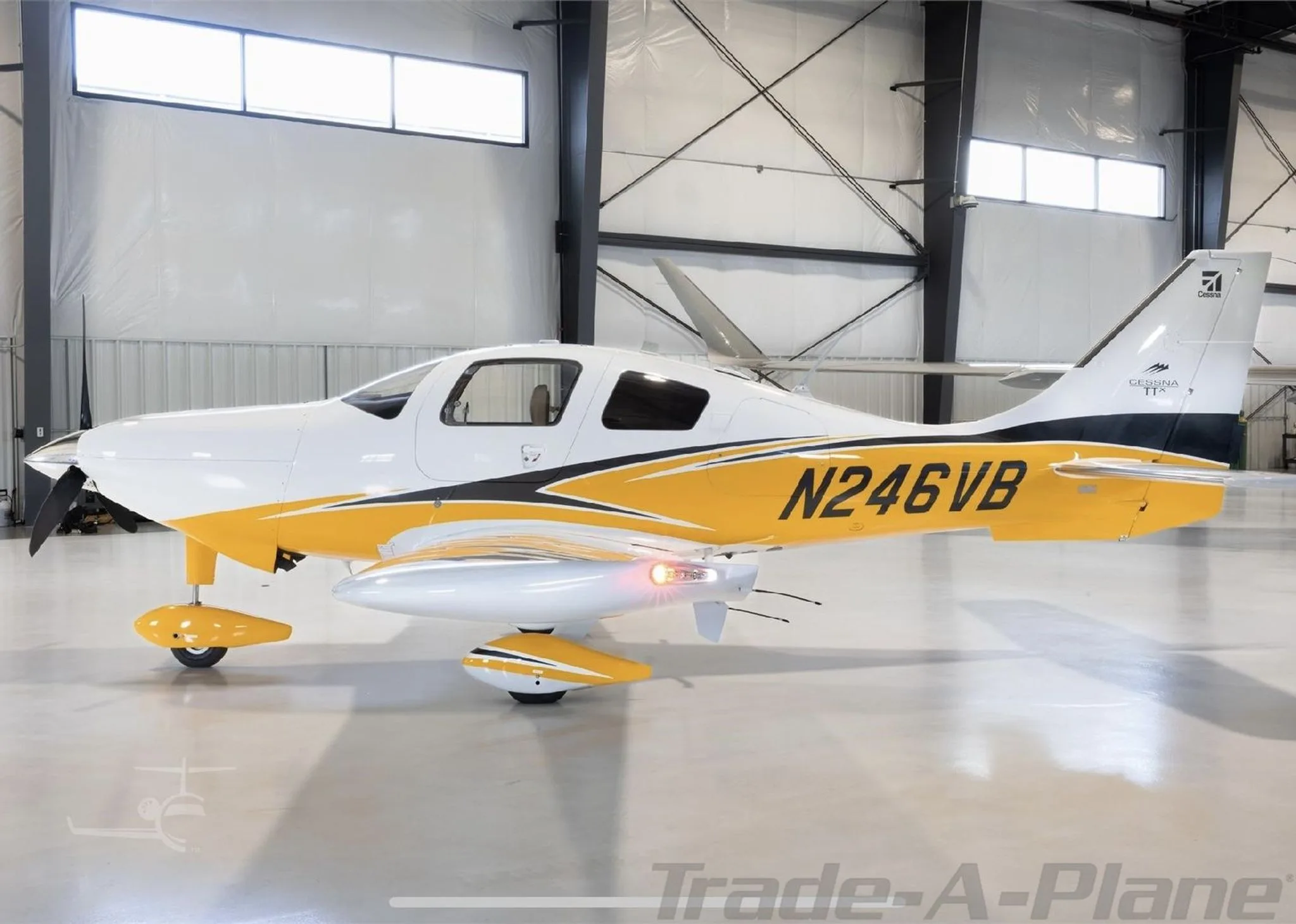 A three-quarter side view of the white and yellow Cessna TTx aircraft N246VB in a hangar.