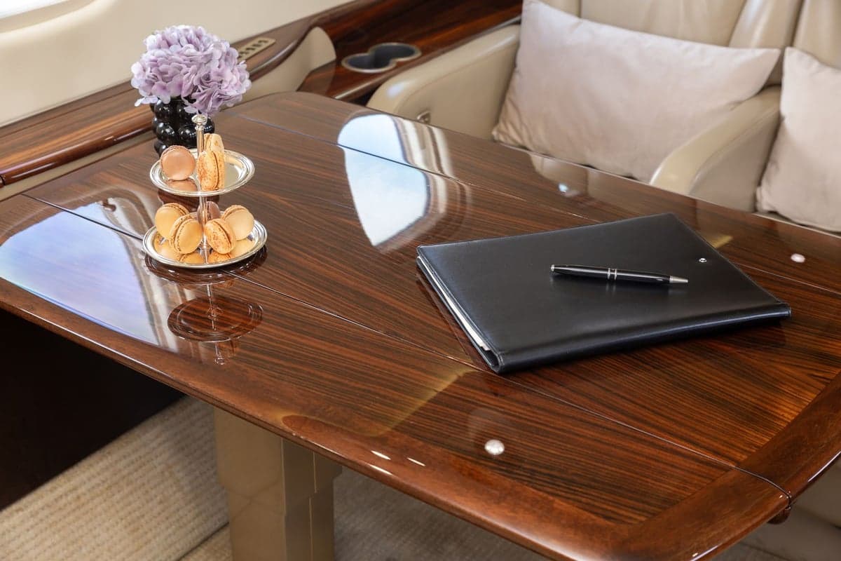 Close up of the wood table with a notebook and pen in the Embraer Legacy 500 cabin.