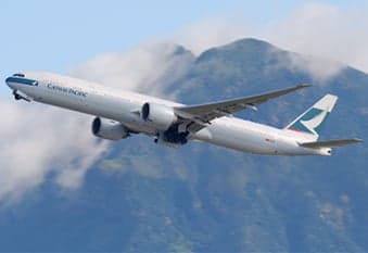 A Cathay Pacific Boeing 777 takes off against a backdrop of mountains and clouds.
