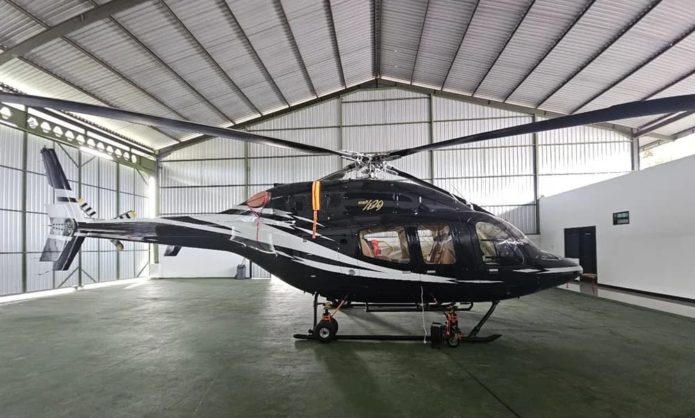 A black and white Bell 429 helicopter with a custom paint scheme parked inside a hangar.
