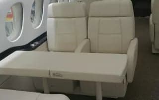 Interior view of the aircraft cabin with cream-colored leather seats and a table.