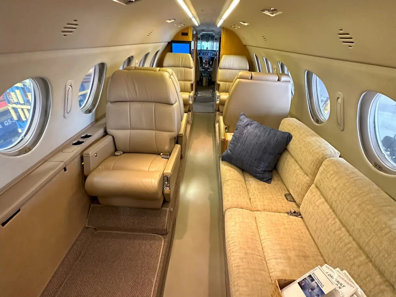 Aircraft cabin interior with beige leather seats and a couch.