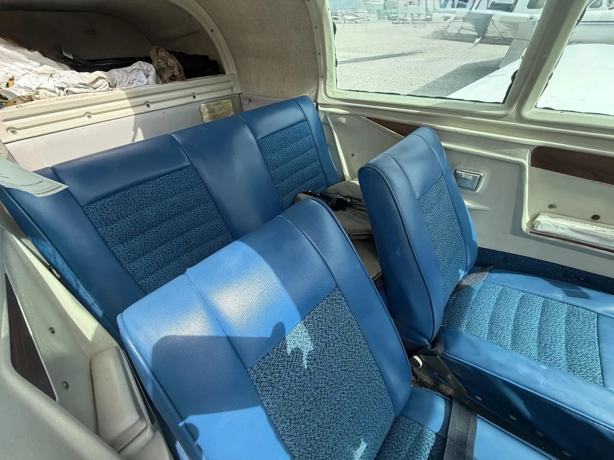 The blue fabric and vinyl interior seats of the aircraft cabin, viewed from the rear.