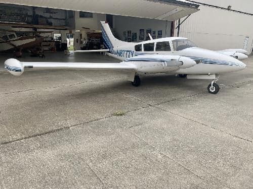 A Piper Aerostar aircraft with blue stripes is parked on the tarmac.
