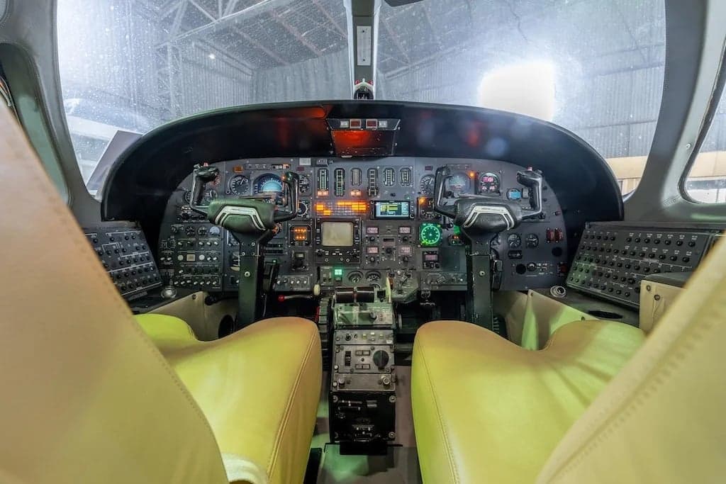 The cockpit of a Cessna Citation II features a full instrument panel and tan leather seats.