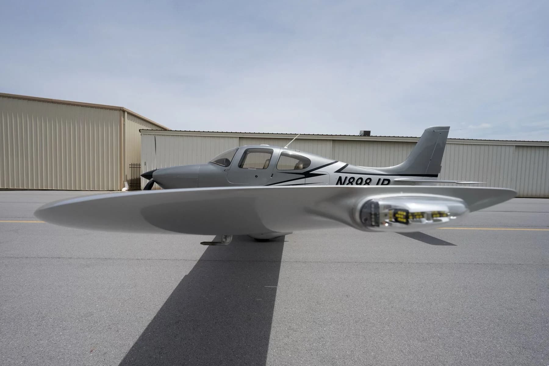 Close-up side view of the silver Cirrus SR22 fuselage and wingtip with landing lights.