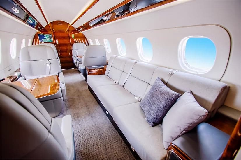 The interior cabin of an Embraer Phenom 300E with seating and wood trim.