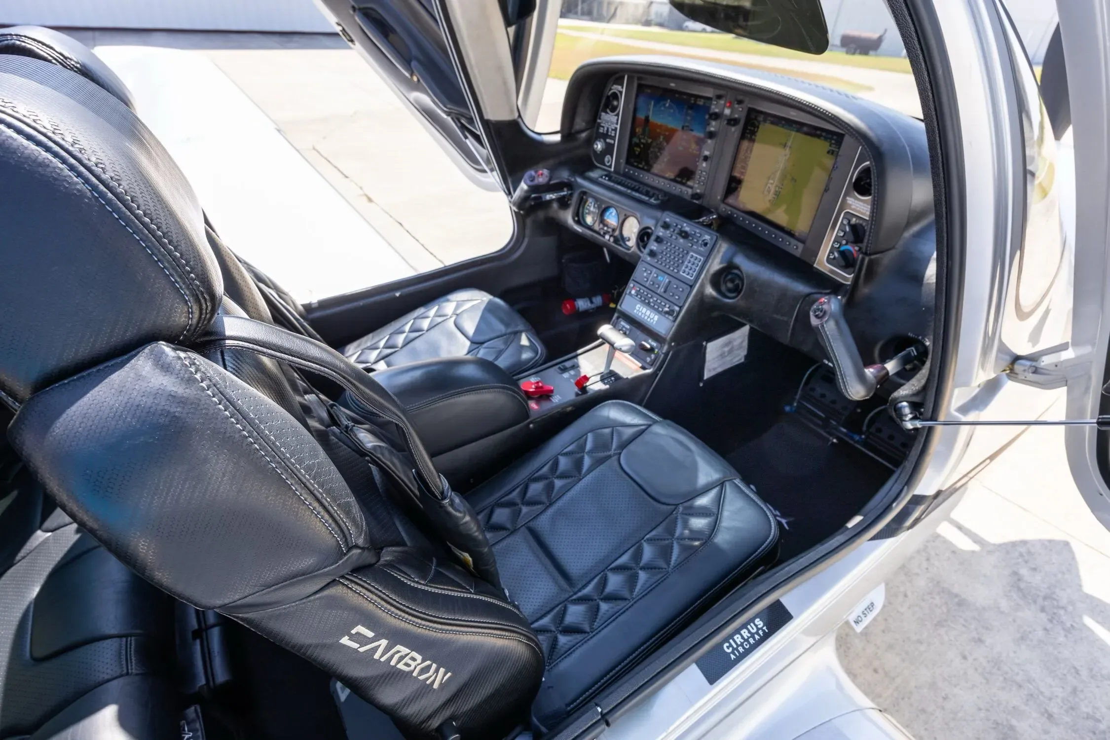 The front cabin and cockpit of a Cirrus SR22, showing black quilted leather seats and the instrument panel.