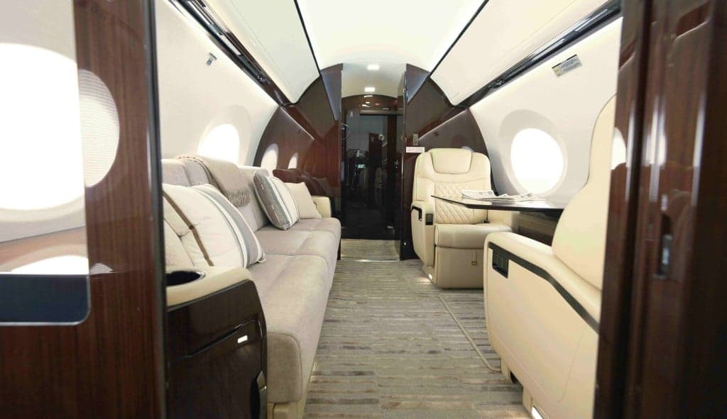 The aircraft's interior features cream-colored leather seats and a patterned carpet.
