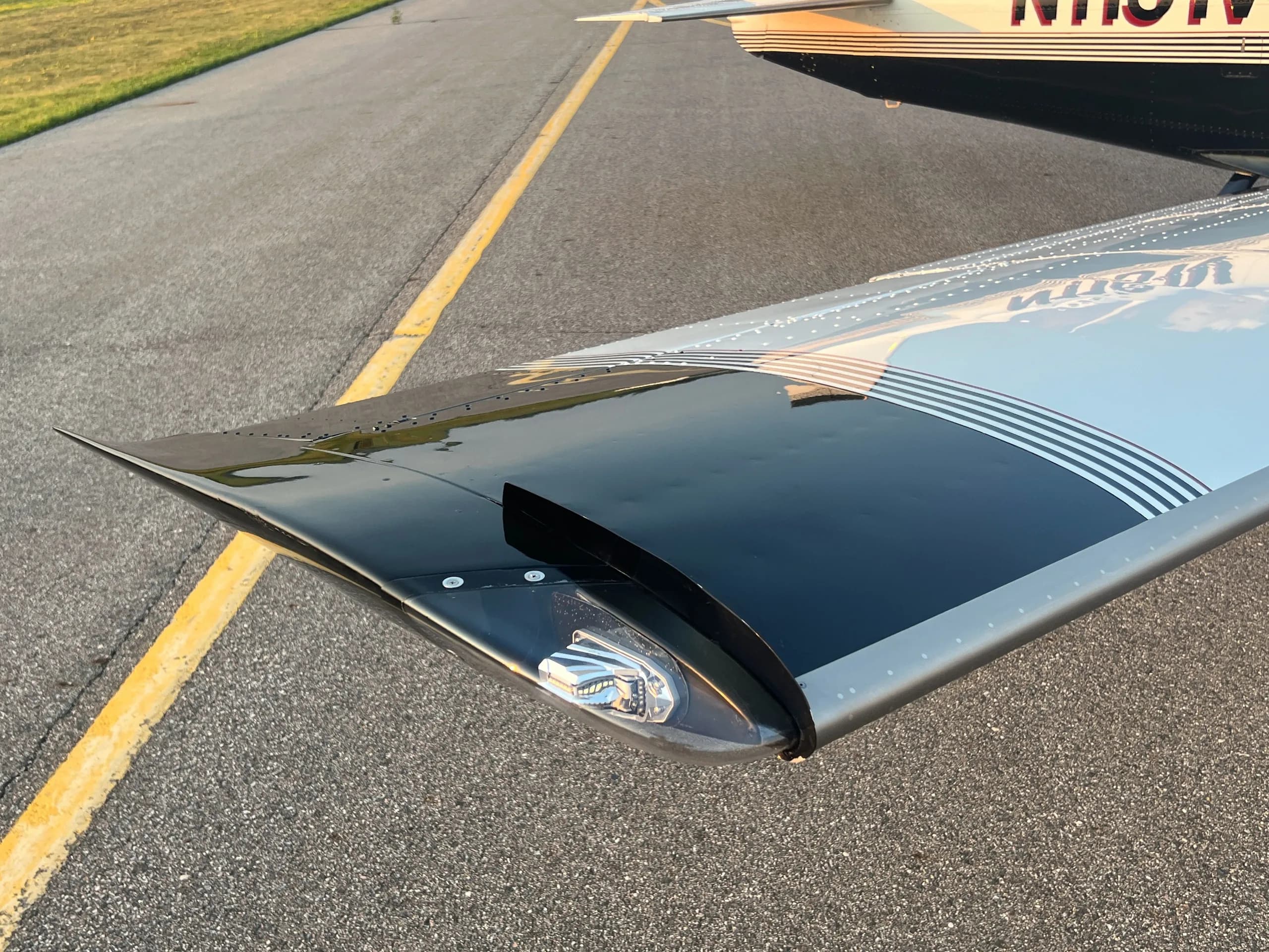 A close-up view of the wingtip of the aircraft, showing the black and white stripe paint scheme.