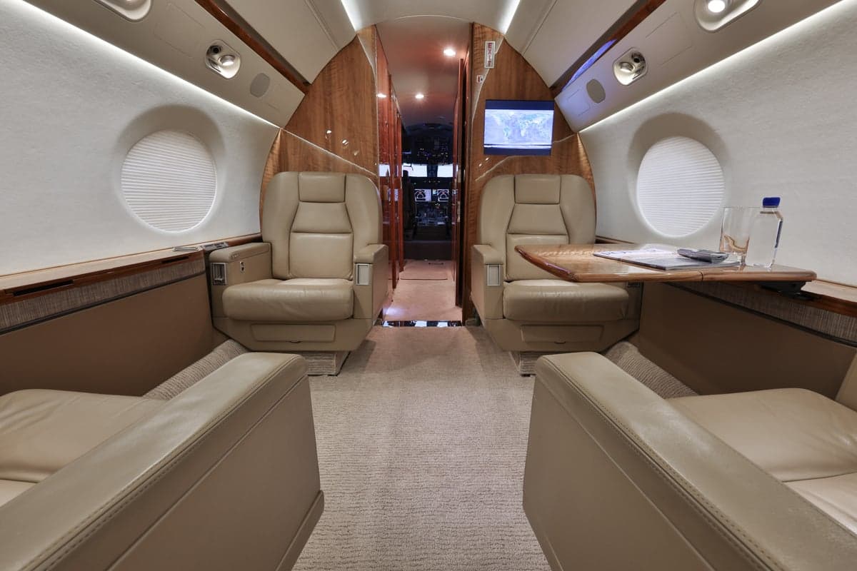 Interior view of the aircraft cabin with leather seats and a table.
