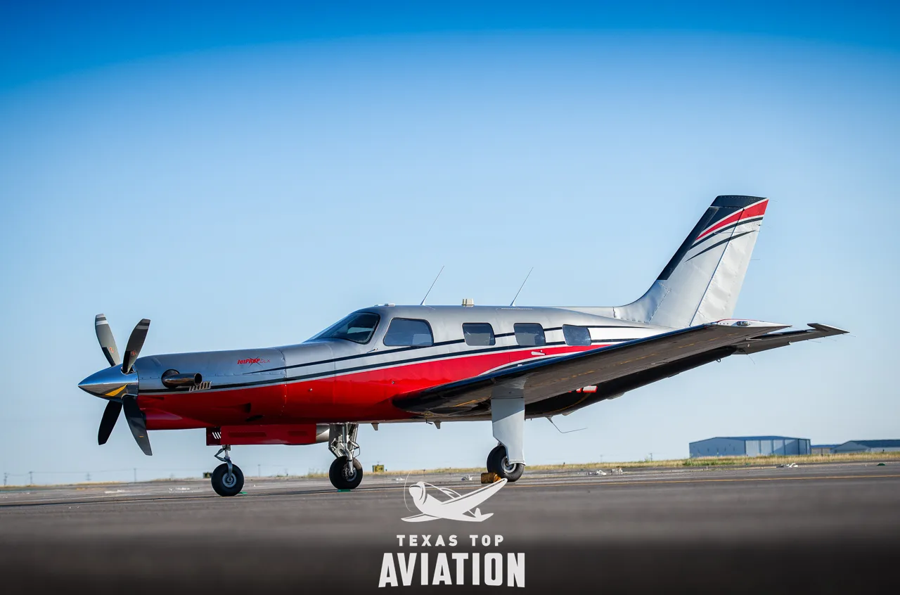 A silver and red Piper Meridian aircraft is parked on the tarmac.