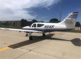 A white and blue aircraft with tail number N114K is parked on the tarmac.