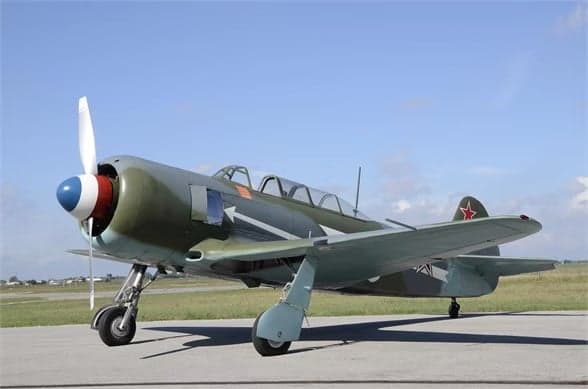 A Lavochkin La-9 parked on the tarmac with a gray and green paint scheme and a red star on the tail.