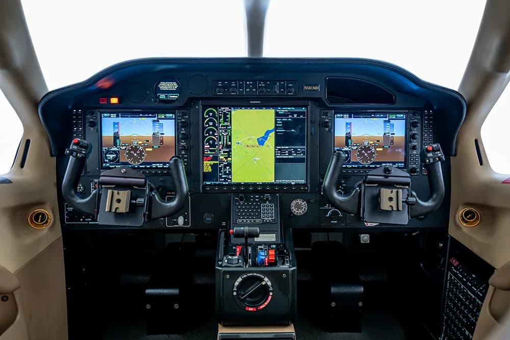 A close-up view of the aircraft cockpit instrument panel with three large digital displays.