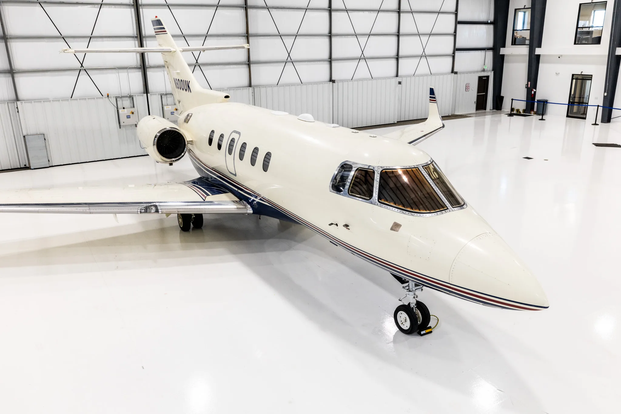 An elevated view of the N800UK business jet parked inside a brightly lit hangar.
