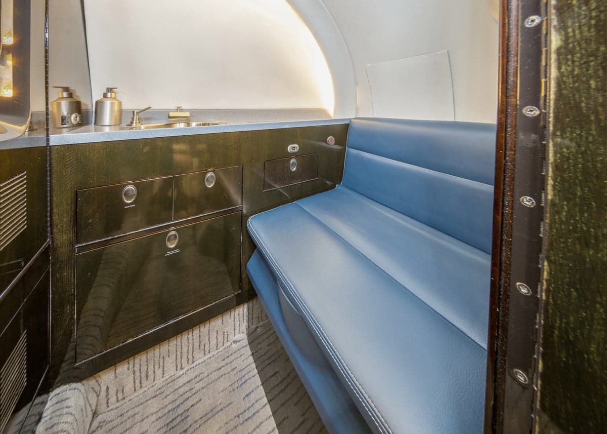 View of the aircraft interior featuring a blue leather bench seat and a sink.