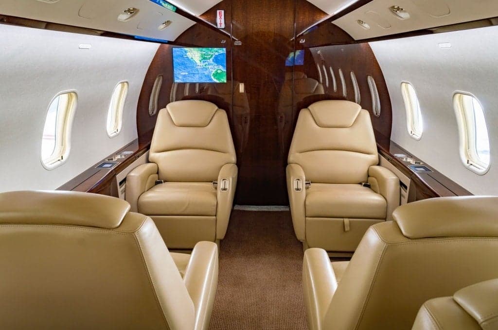 Interior view of the aircraft cabin with leather seats and wood trim.