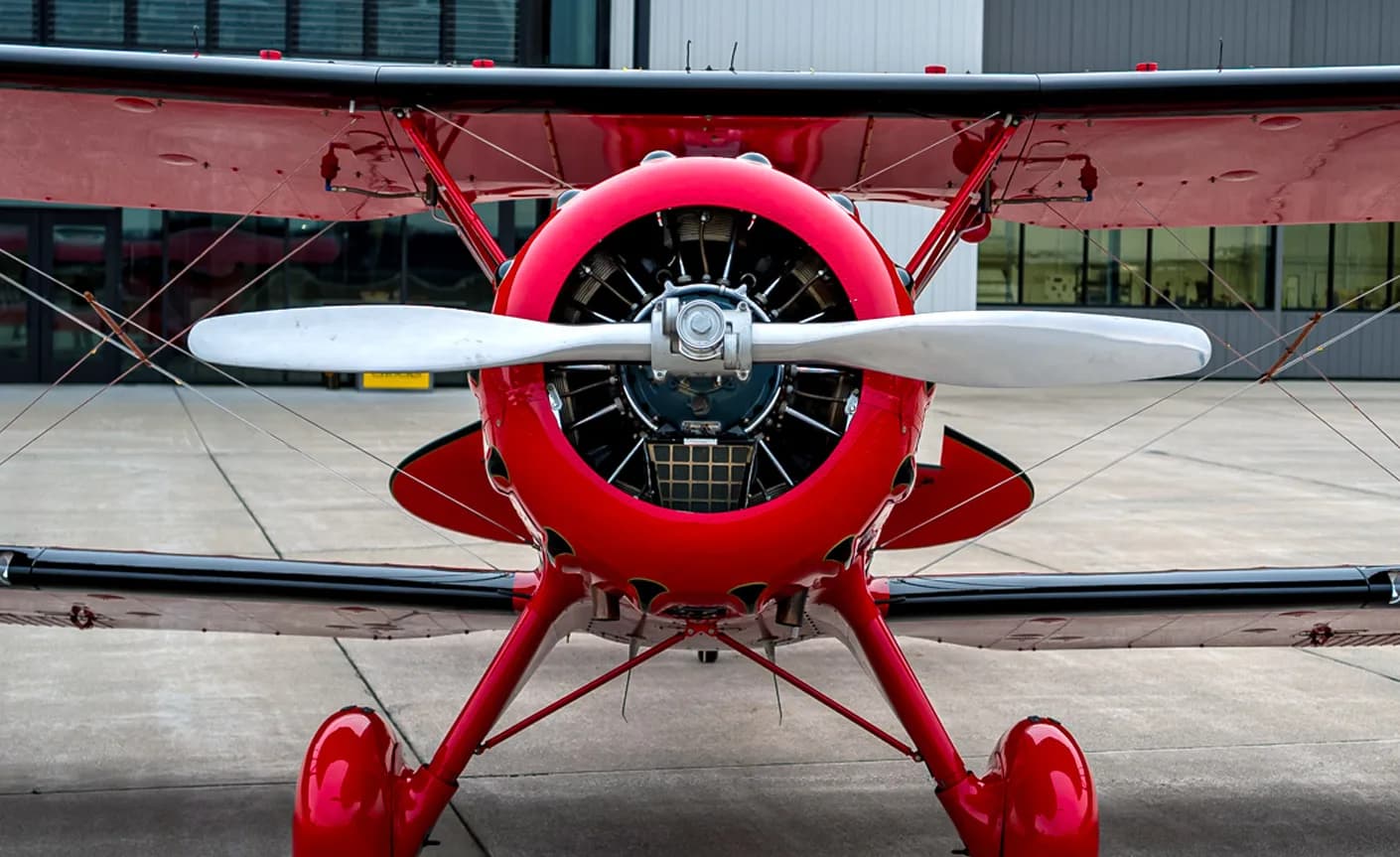 Front view of a red biplane with a silver propeller.