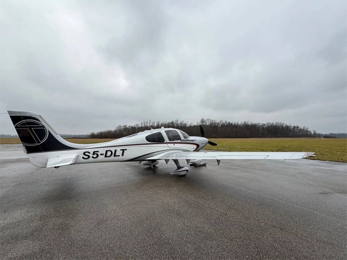 A Cirrus SR22 aircraft with a white and black paint scheme parked on the tarmac.