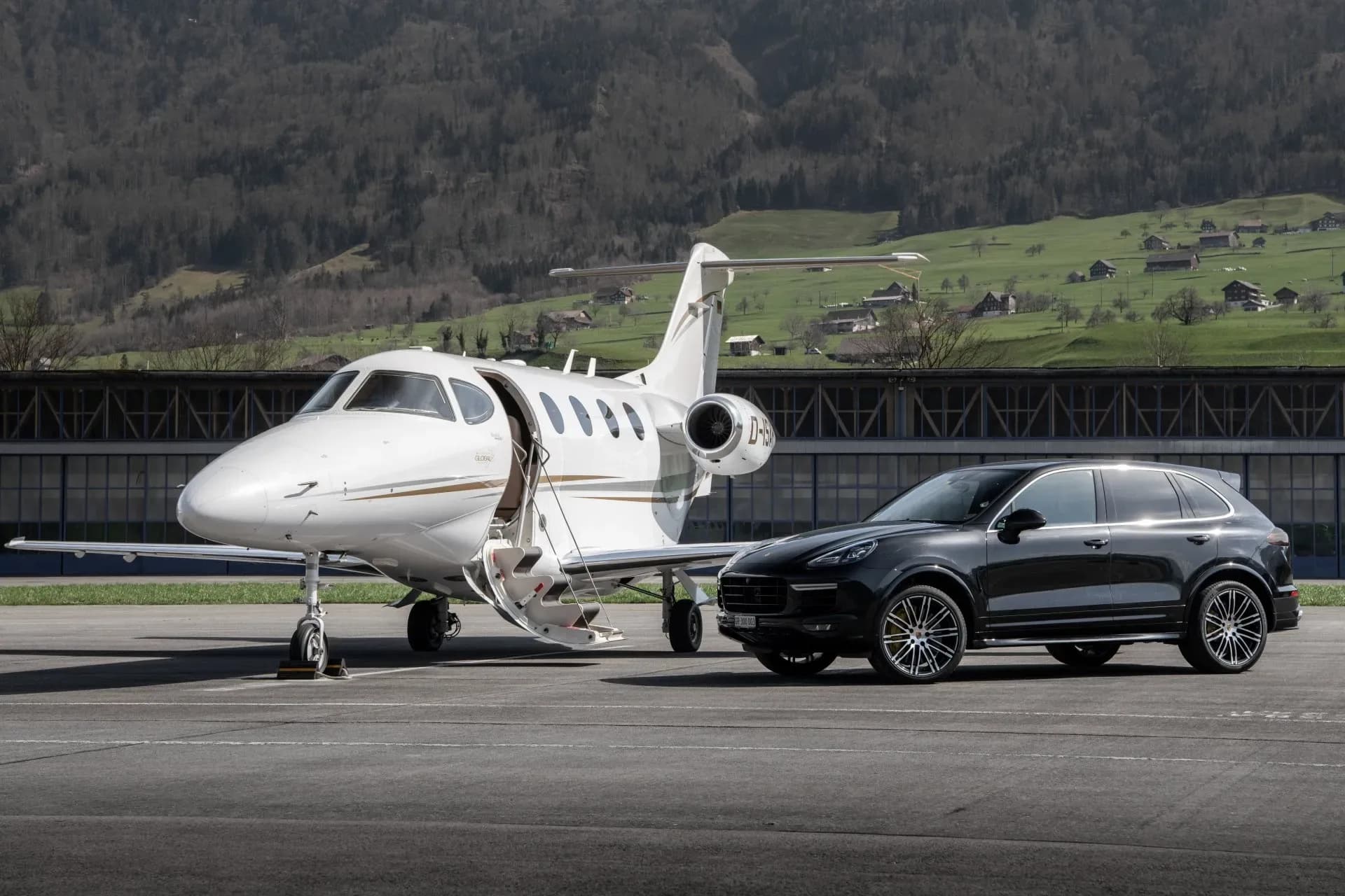A white jet with gold trim sits on the tarmac next to a black SUV.