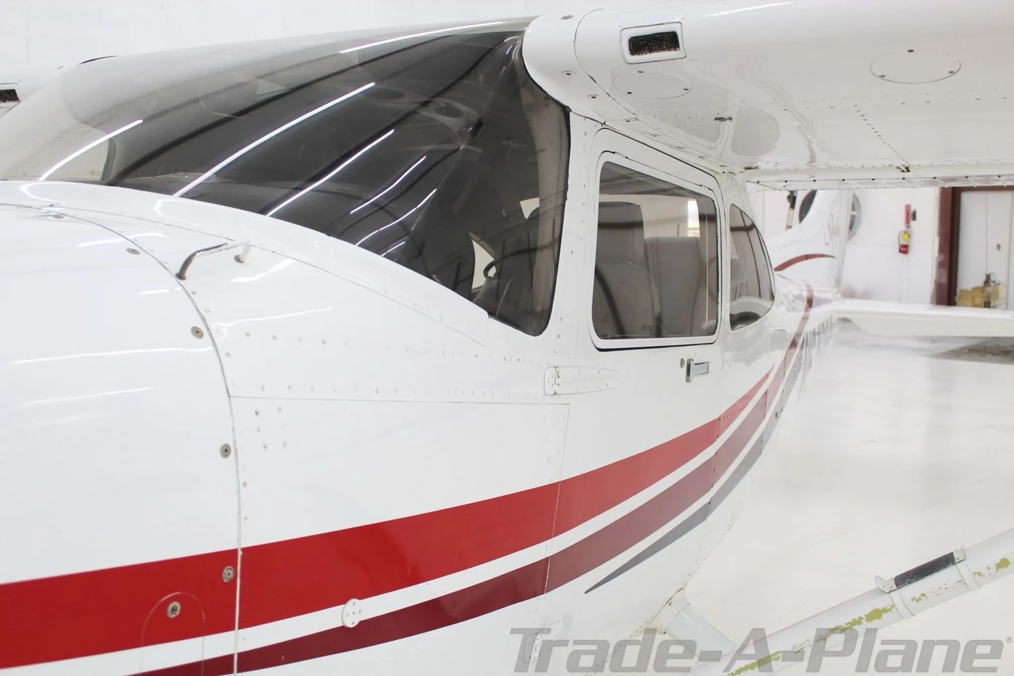 A close-up view of the cockpit window and side of the fuselage of the Cessna Skylane N6768R.