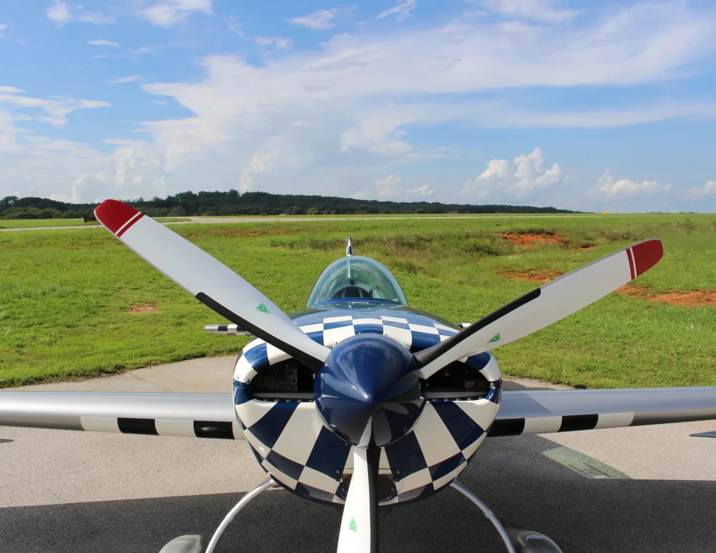 A close-up front view of the N51E Extra EA-300/L aircraft, highlighting its blue and white checkered propeller spinner.