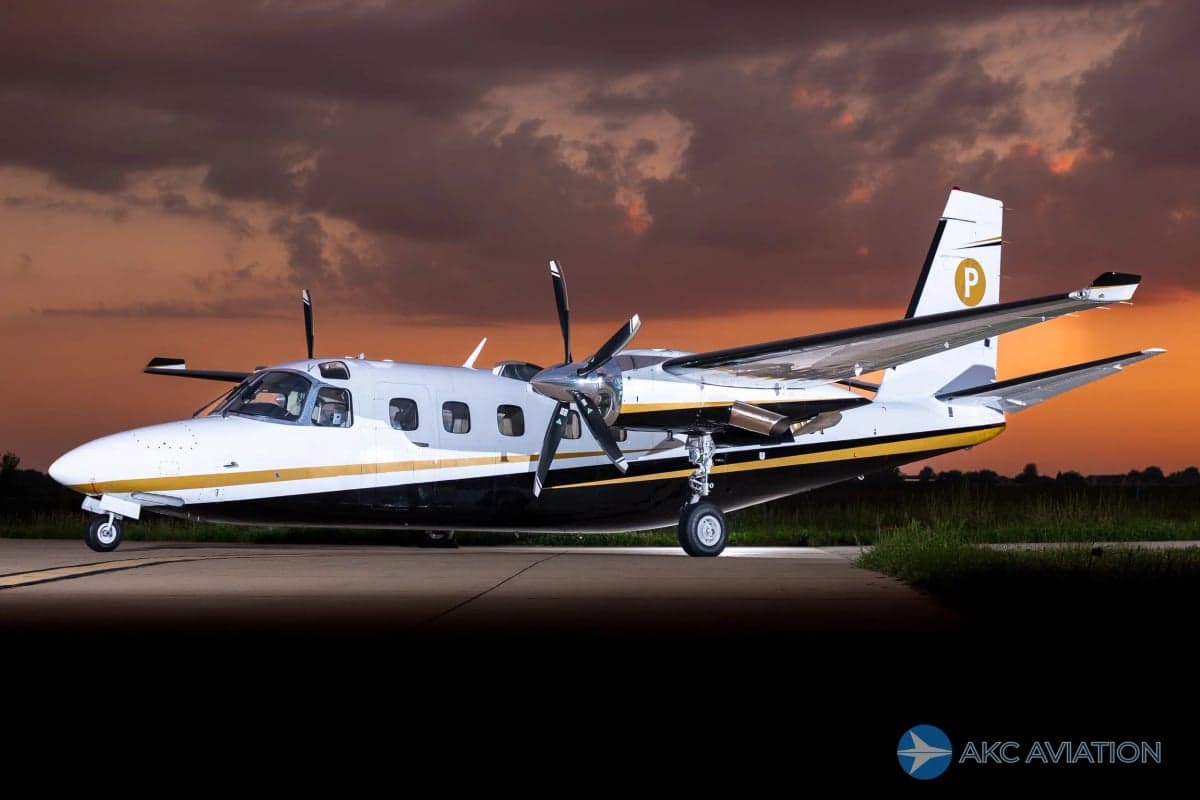 A Twin Commander aircraft on the tarmac at sunset.