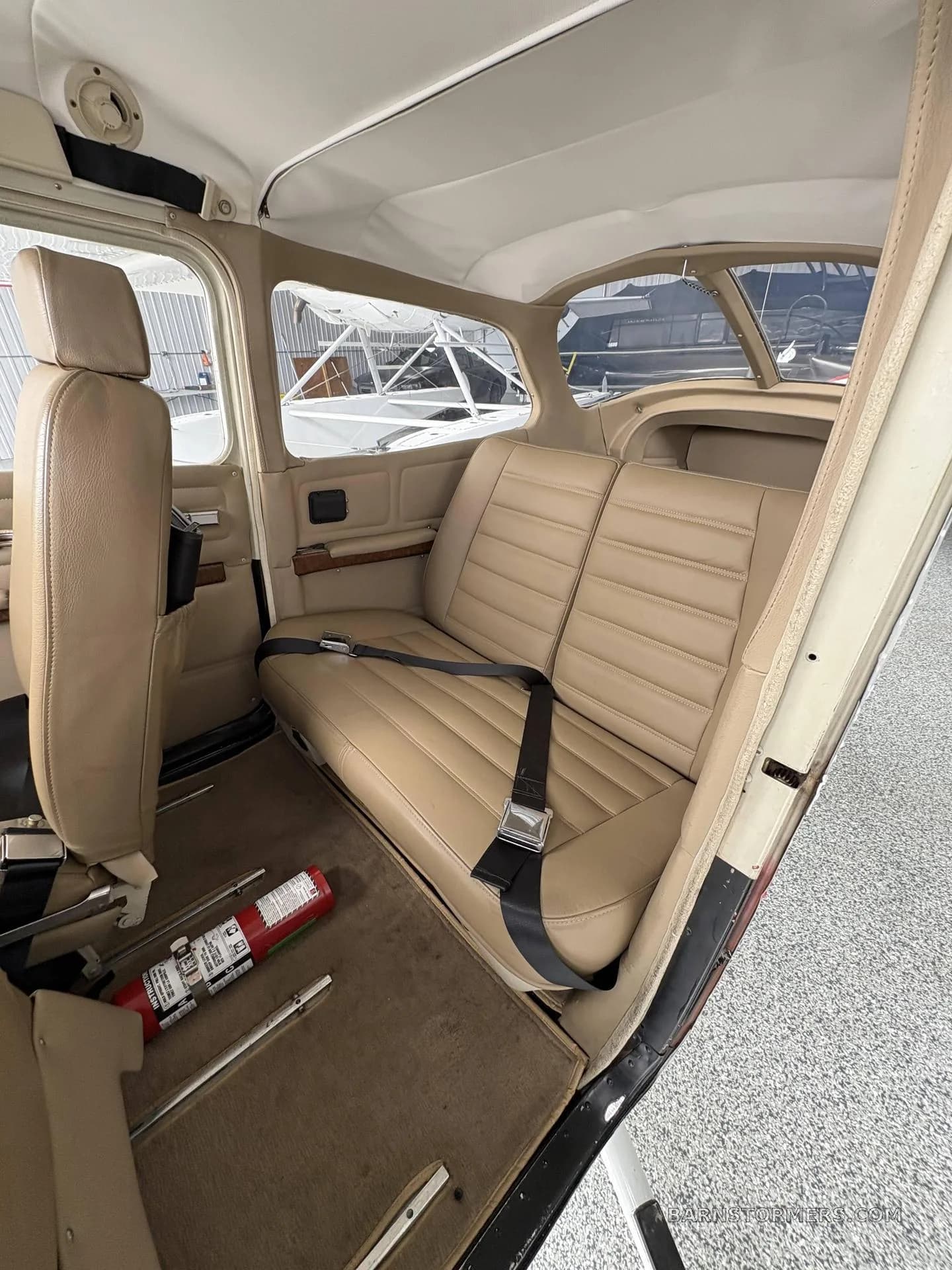 The tan leather rear passenger seats of a small aircraft cabin.