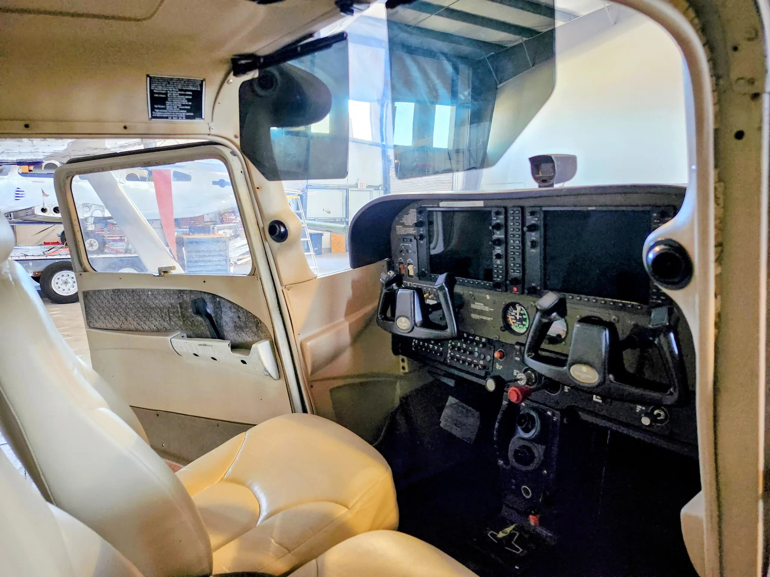 View from inside the aircraft cabin showing the beige seats and the cockpit panel.