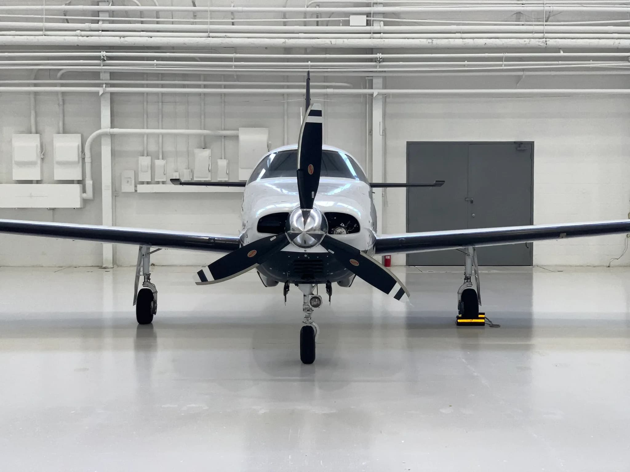 A head-on view of the white and black Piper Mirage aircraft (N891AW) with its propeller, parked in a hangar.