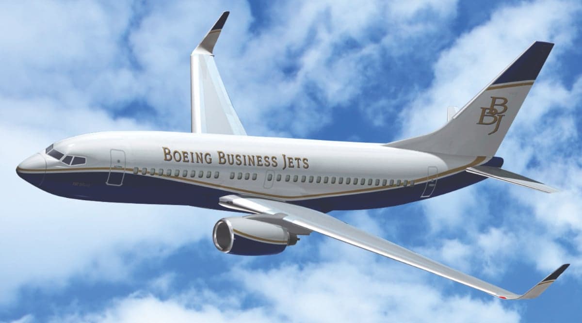 A Boeing Business Jet in flight against a cloudy sky.