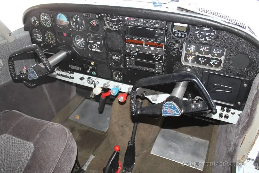 The detailed instrument panel and dual yokes of a small aircraft cockpit.