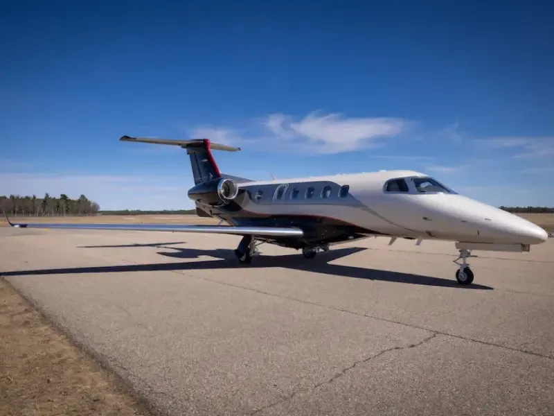Side view of a white and black Phenom aircraft on the tarmac.