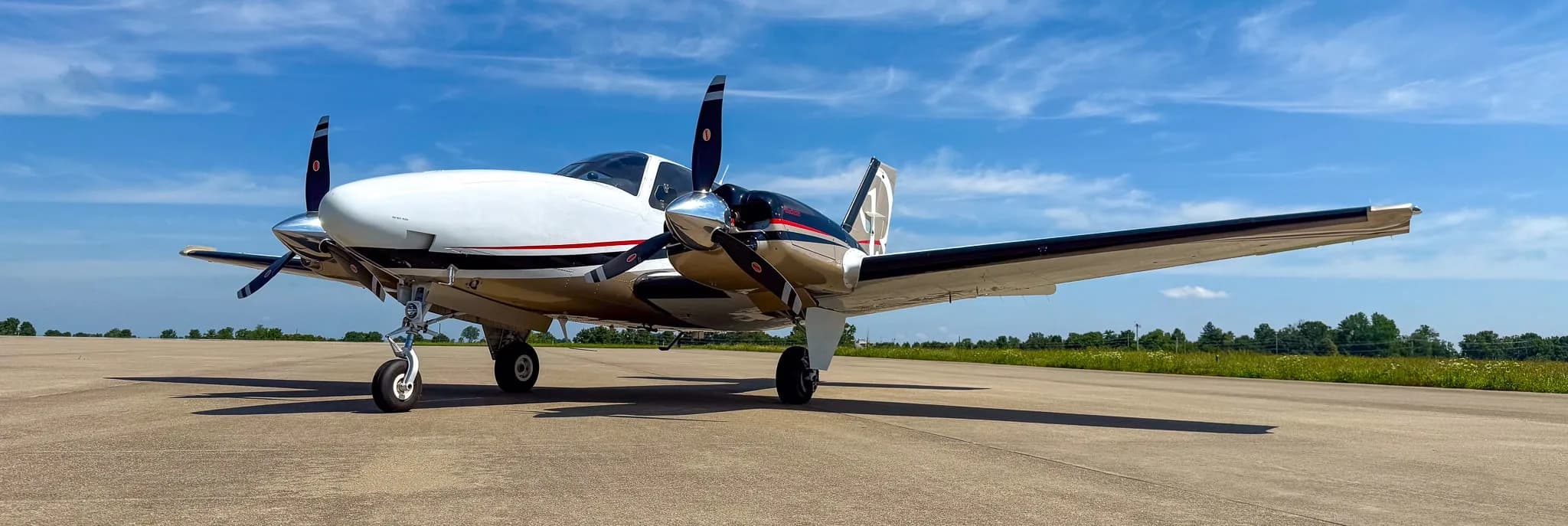 Low angle view of a white and gold twin-engine Beechcraft Baron G58 on an airfield.