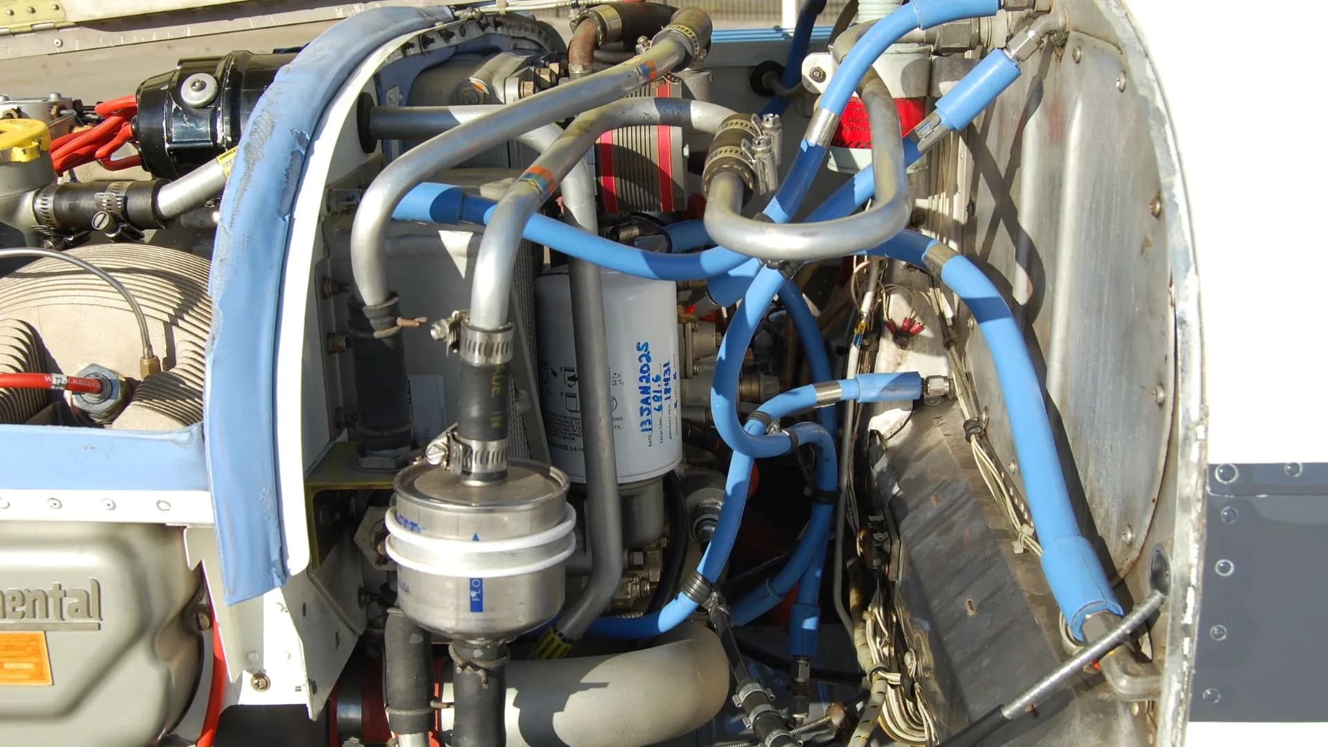 Close-up of the engine compartment of a Beechcraft Bonanza, showing various components and hoses.