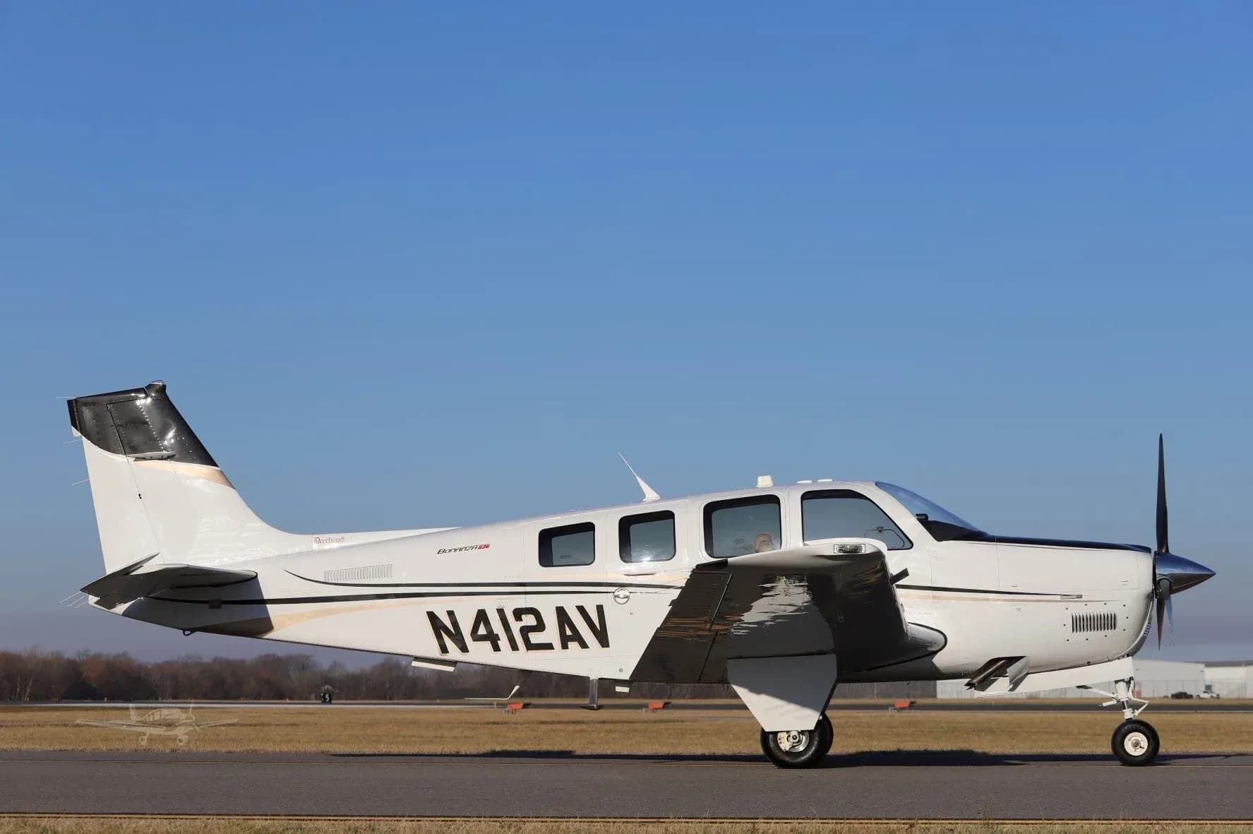 A white Beechcraft Bonanza G36, registration N412AV, seen from the side on a runway.
