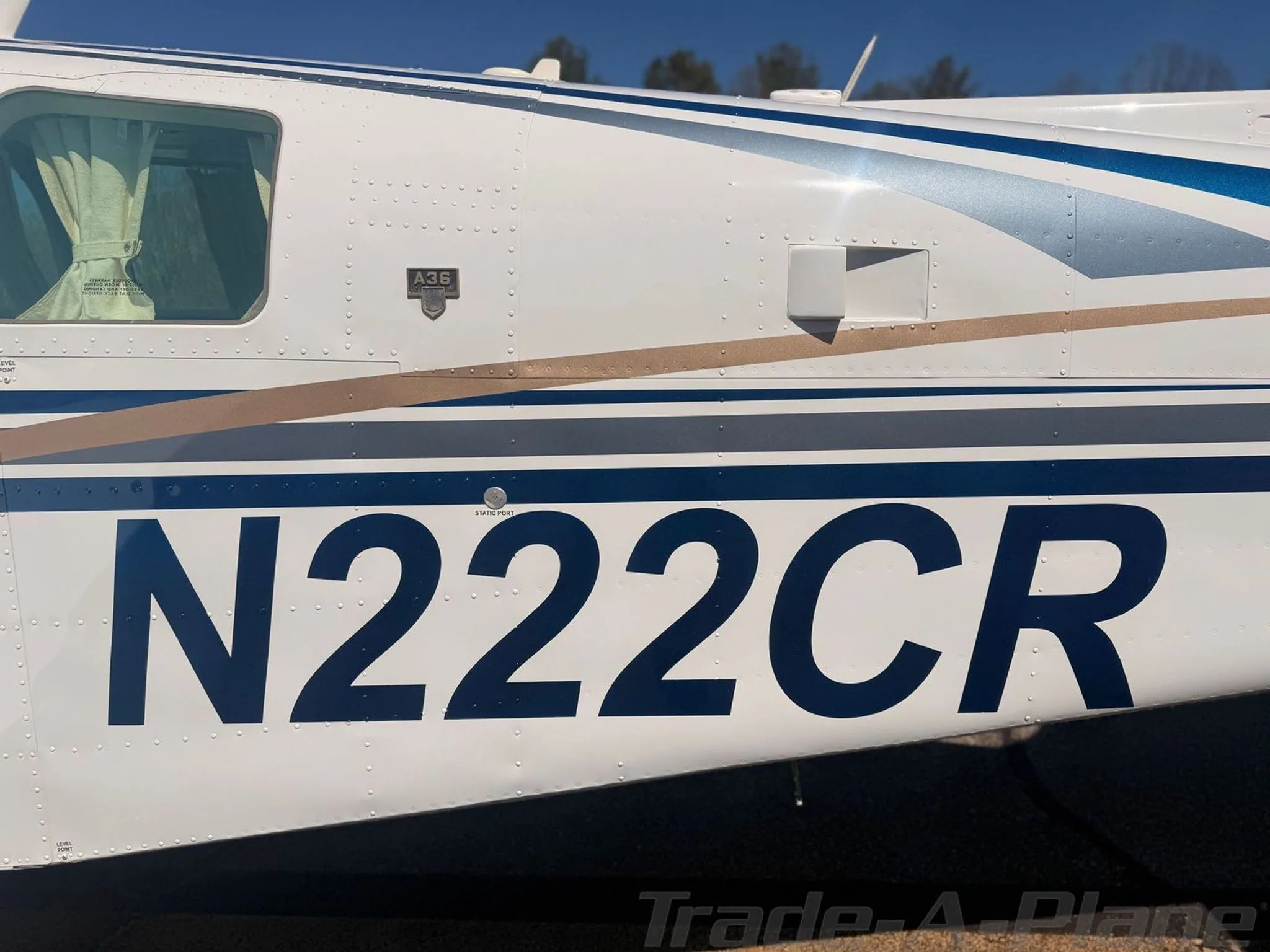 A close-up of the fuselage of N222CR, showing the registration number and blue and gold stripe details.