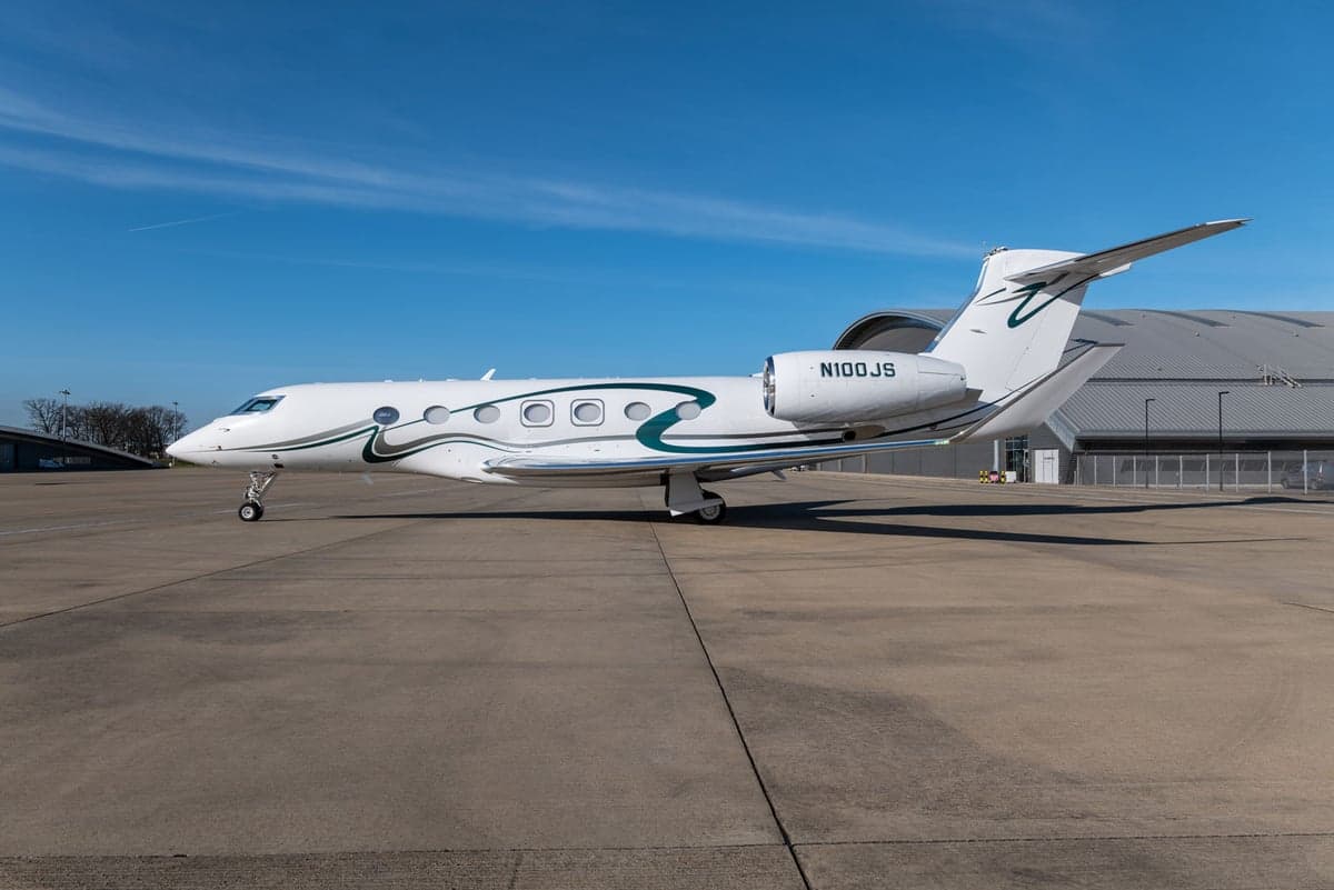Gulfstream aircraft N100JS parked on the tarmac with a white and green paint scheme.