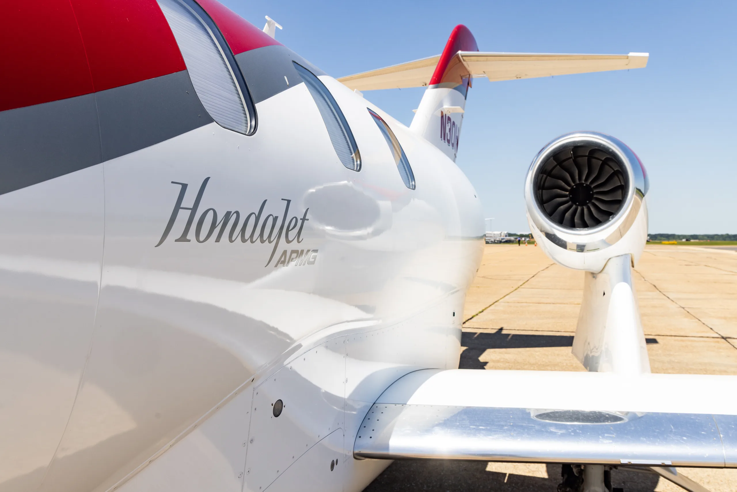 Close-up view of the white fuselage and engine of a HondaJet HA-420 (N30HJ), showing "Hondajet APMG" text.