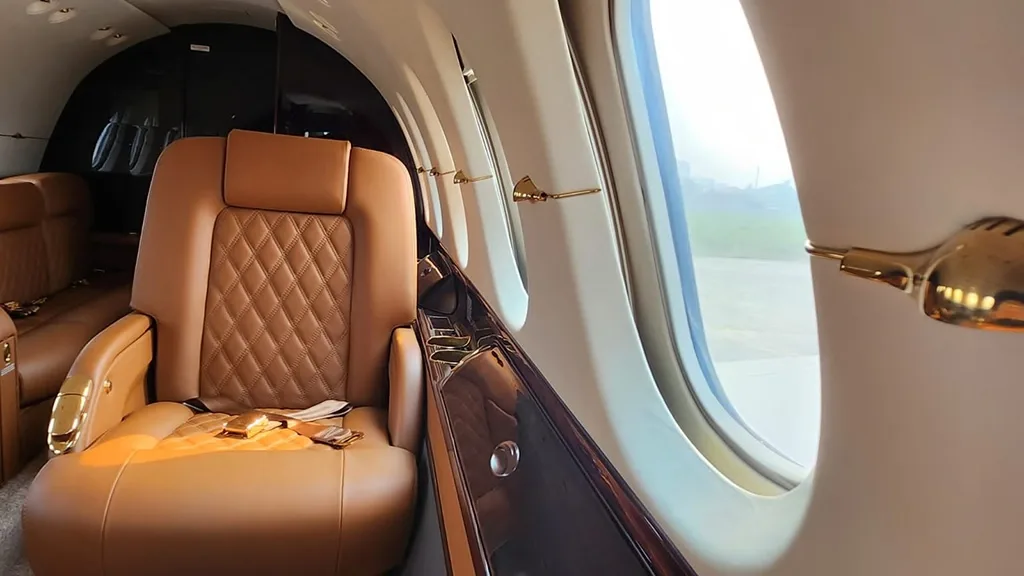 A close-up view of a quilted brown leather seat next to a window in an aircraft cabin.