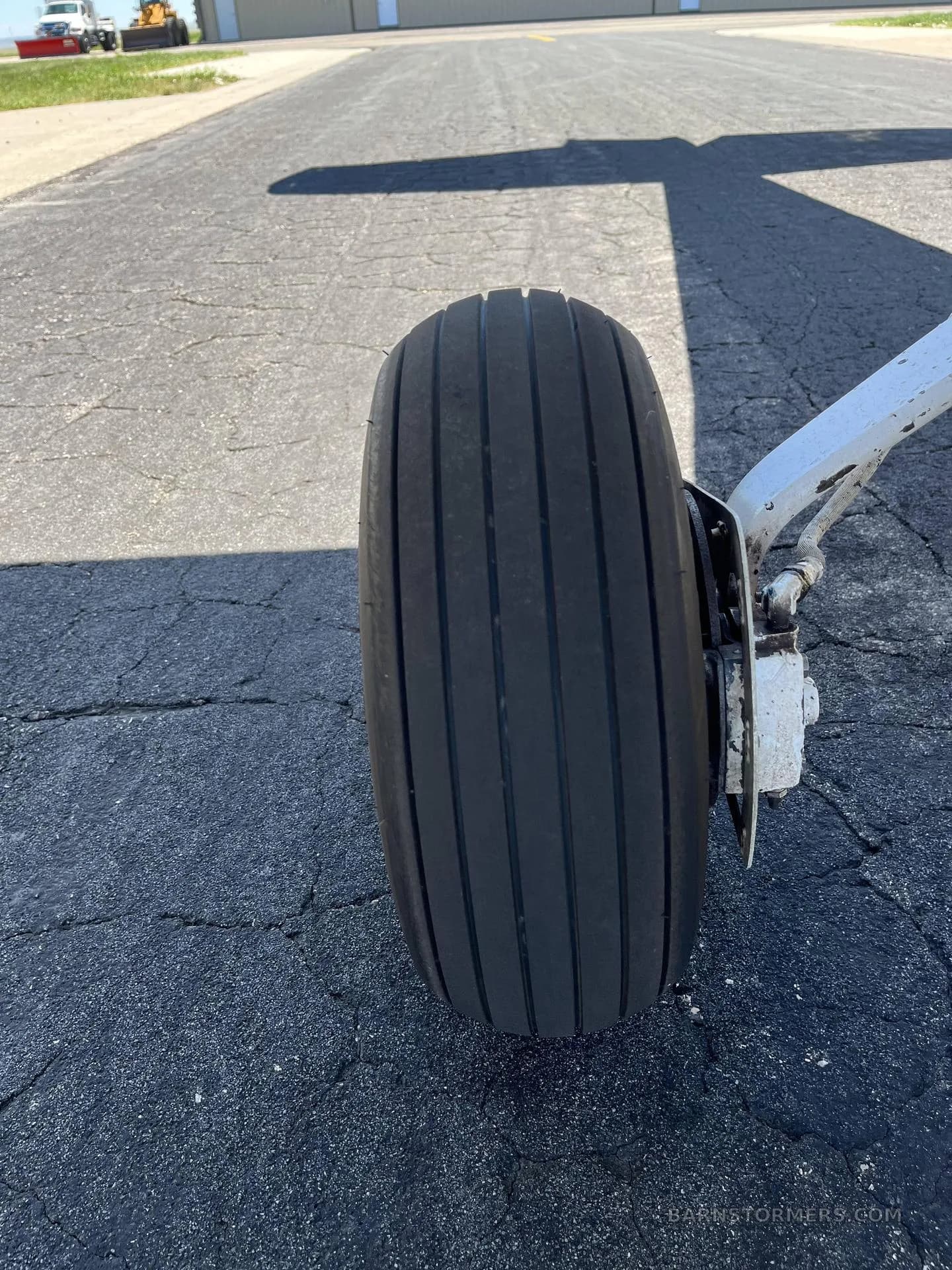 A close-up view of the main landing gear wheel and tire of a small aircraft on an asphalt surface.