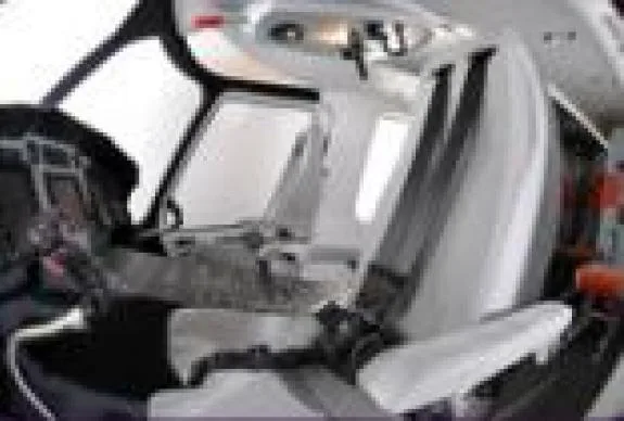 View of the aircraft cockpit with white seats and instrument panel.