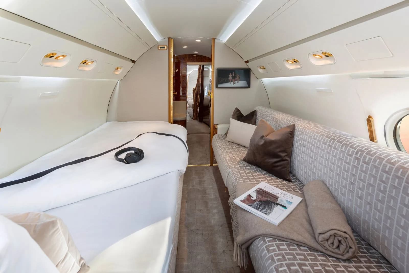 A luxurious aircraft interior with a bed, a couch, and wood accents.