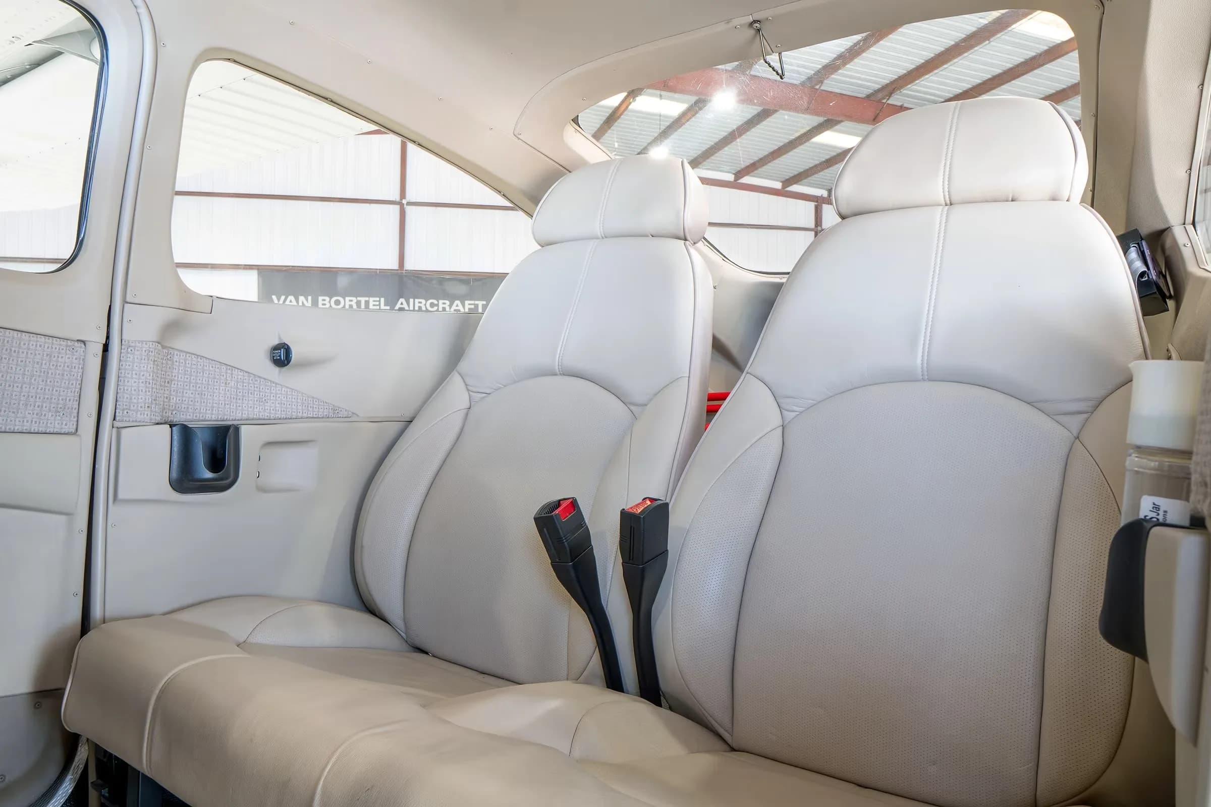 The light beige leather rear passenger seats of a Cessna Skylane cabin.