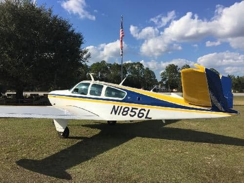 A Beechcraft Bonanza aircraft with registration N1856L is parked on the grass.