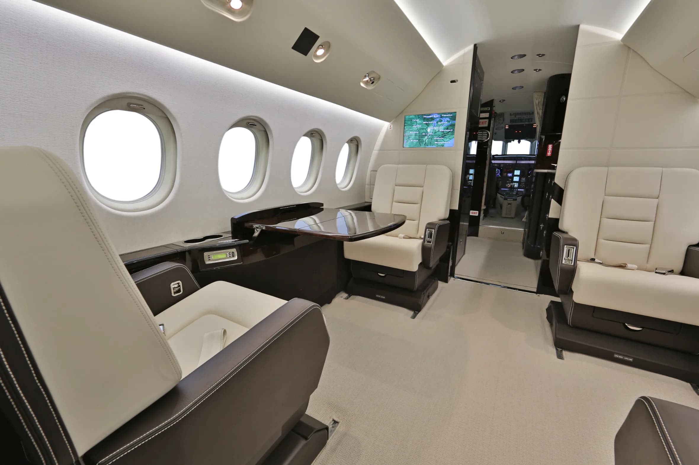 View of the aircraft's interior with white leather seats and a table.